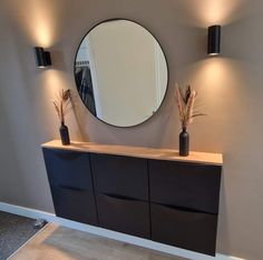 a bathroom with a round mirror on the wall and two vases in front of it