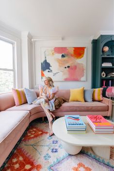 a woman sitting on top of a pink couch in a living room