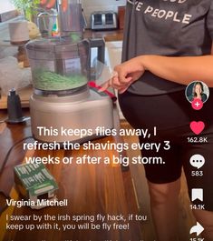 a woman standing next to a blender filled with liquid