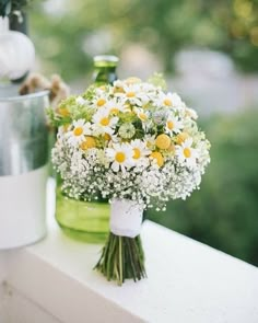 a bouquet of daisies and baby's breath on a ledge