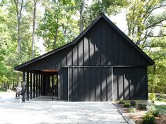 a large black building surrounded by trees in the woods