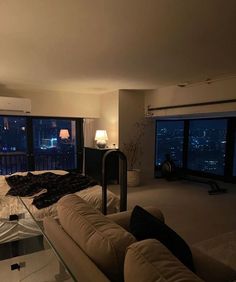 a living room filled with furniture next to large windows and a view of the city at night