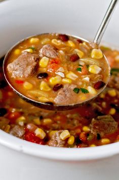 a spoon full of soup with corn and meat