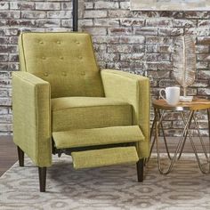 a green chair sitting on top of a rug next to a table with a cup