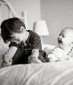 two babies playing on the bed with each other