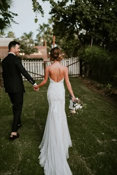 a bride and groom holding hands in the grass