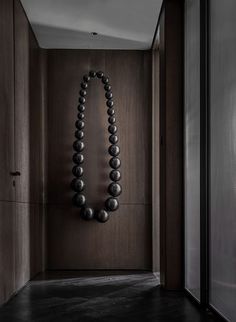 a black beaded necklace hangs on the wall next to an open door in a dark room