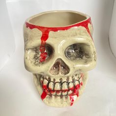 a white and red skull vase with blood dripping down the side, on a white background