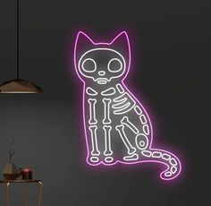 a neon cat sitting on top of a table next to a lamp