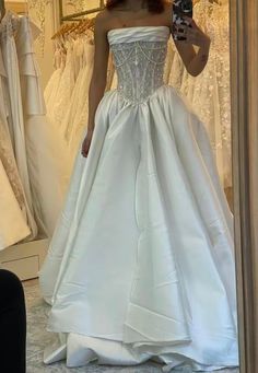 a woman taking a selfie in front of a mirror wearing a white wedding dress