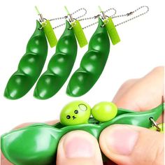 three peas are being held in front of each other by two hands with green beads attached to them