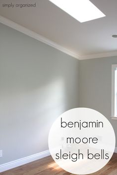 an empty room with white walls and wood flooring in the corner, has a round sign that says benjamin moore sleigh bells