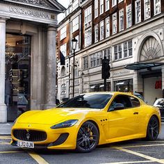 a yellow sports car parked in front of a building on a street with traffic lights