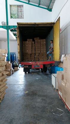 a man is loading boxes into the back of a moving truck in an industrial warehouse