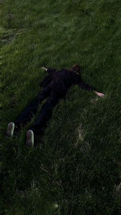 a person laying in the grass with their head down