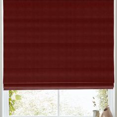 a red roman blind in front of a window with vases on the windowsill