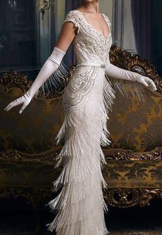 a woman in a long white dress standing next to a couch with the words, these incredible wedding gowns will bring out your inner flapper girl