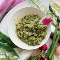 a white plate topped with asparagus and pesto next to radishes