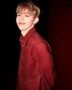 the young man is wearing a red shirt and posing for a photo in front of a black background