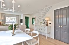 a living room filled with furniture and a white table in front of a doorway that leads to a bedroom