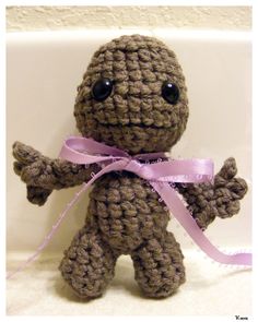 a crocheted stuffed animal with a pink ribbon around its neck