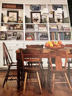 a dining room table and chairs with bookshelves in the backround behind them