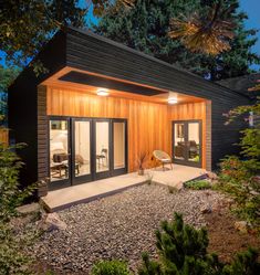 a small wooden building sitting in the middle of a forest at night with lights on