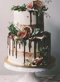 a three tiered cake decorated with figs and leaves