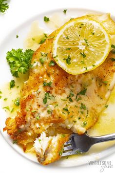 a white plate topped with fish and lemon slices