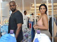 a man and woman standing next to each other in front of a clothing store window