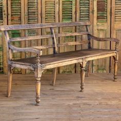 an old wooden bench sitting on top of a hard wood floor next to shutters