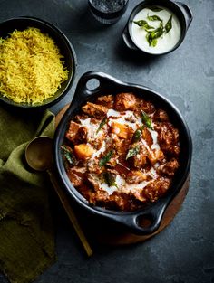 a skillet filled with meat and rice next to other dishes