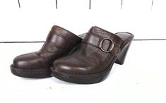 "Dark brown leather Born clogs/leather wedge sandals/Born slip on mules/shoes/38/7 Measurements... -marked size: 38/7 -insole: 9.5\" -width at ball: 3.25\" -heel: 3.5\" Features... -leather upper in a dark brown hue -decorative leather belt buckle detail -classic clog slip on style -padded leather insole -chunky rubber wedge heel -brand: Born Condition... -great vintage condition -some wear on soles but still in great shape -minor scuffing on heels -gently worn 1I3215" Leather Platform Slip-on Mules, Leather Wedge Heel Slip-on Clogs, Casual Wedge Heel Mules With Heel Loop, Casual Mules With Heel Loop And Wedge Heel, Casual Mules With Wedge Heel And Heel Loop, Casual Platform Mules With Pointed Toe, Brown Mules With Leather Footbed And Wedge Heel, Casual High Heel Leather Mules, Casual Leather High Heel Mules