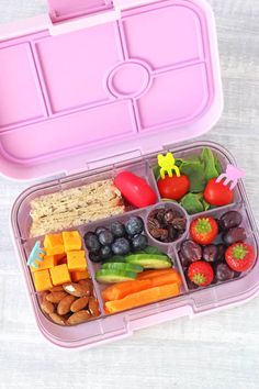 a pink lunch box filled with fruits and vegetables