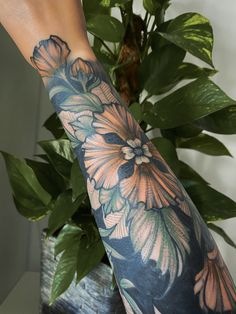 a woman's arm with flowers and leaves on it