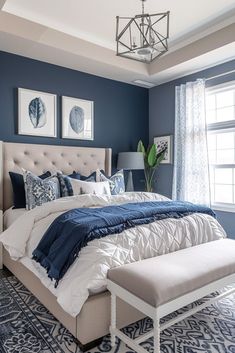 a bedroom with blue walls, white bedding and an upholstered headboard