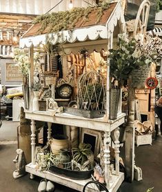 an old fashioned store display with plants and other things on it's stand,