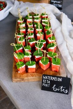 watermelon and mint bites are displayed on a wooden platter with a sign