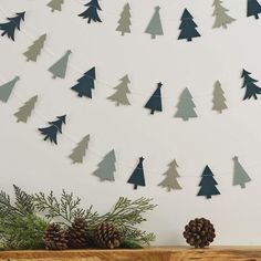 a wooden table topped with pine cones and evergreen branches next to a wall hanging decoration