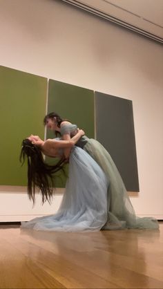 two people are dancing in front of some paintings