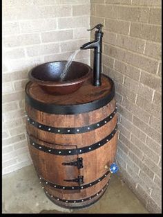 a wooden barrel with a faucet and sink in the corner next to a brick wall