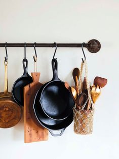 pots and pans are hanging on the wall next to a cutting board with utensils