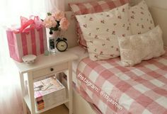 a pink and white checkered bedspread on a small table in front of a window