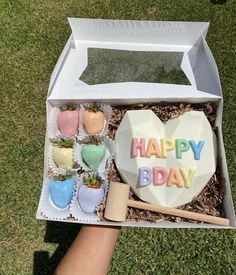 someone is holding up a happy day heart shaped cake in a box with strawberries on it