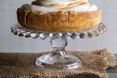 there is a pie on a glass cake stand with whipped cream in the top and bottom