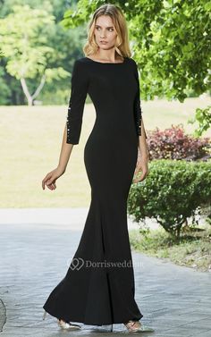 a woman in a long black dress is walking down the street with her hand on her hip