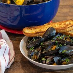 a bowl filled with mussels next to bread