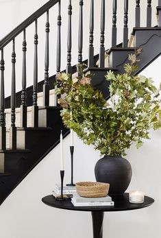 a black table with a plant and candles on it in front of a stair case