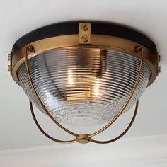 a ceiling light with a circular glass shade on the top and metal trim around it