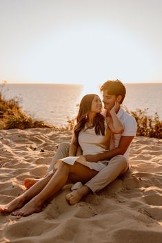 a man and woman are sitting on the sand